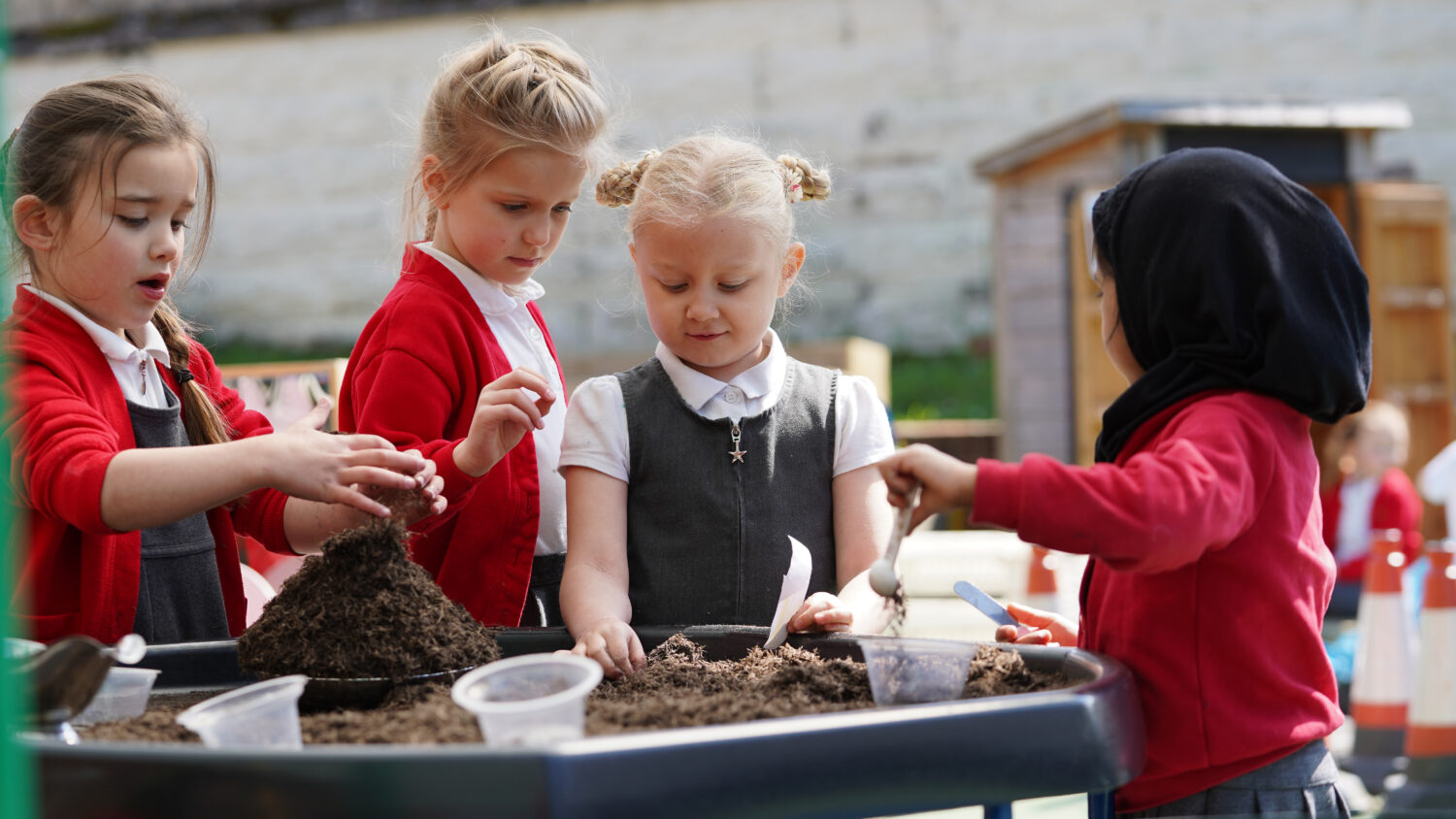 Several students stood around a sandbox