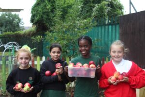 4 students holding baskets of apples