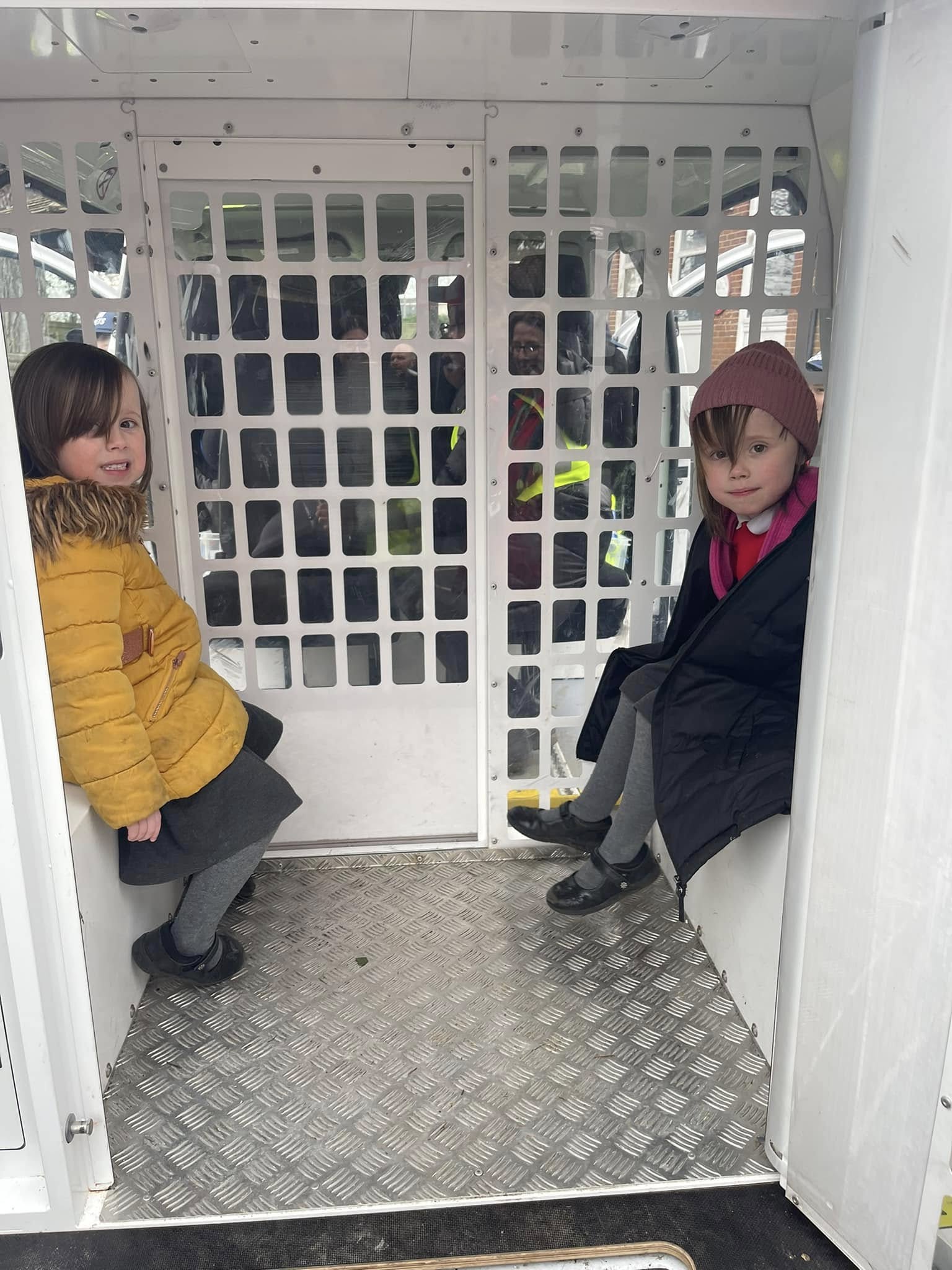 2 students sitting in the back of a police car