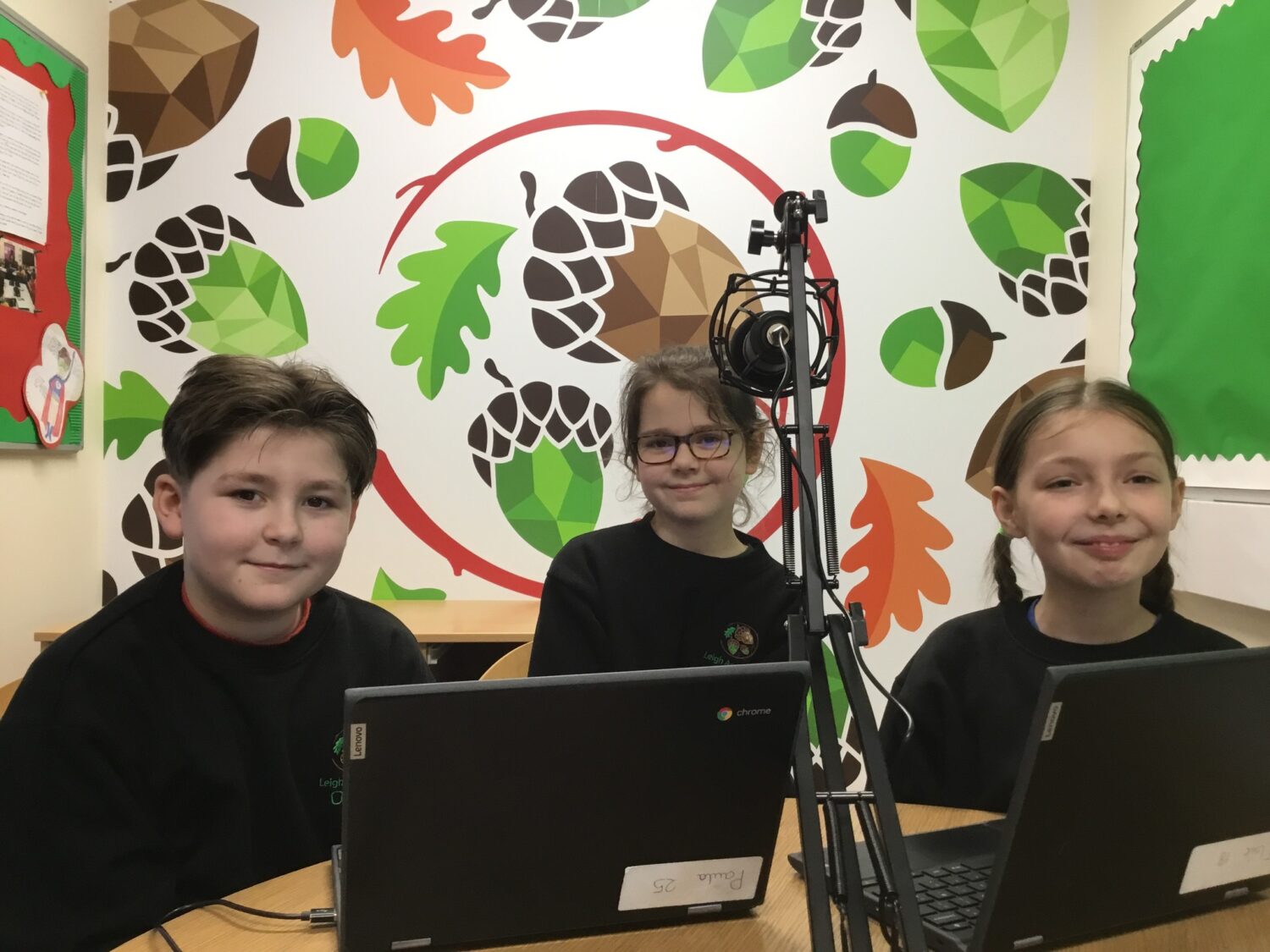 3 students smiling, sat behind a microphone